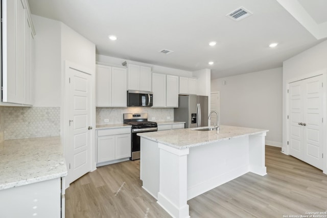 11554 Cottage Pt, San Antonio, TX 78254 - kitchen with stainless steel appliances, light wood-style flooring, white cabinets, a center island with sink, and backsplash
