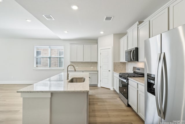 11554 Cottage Pt, San Antonio, TX 78254 - kitchen with stainless steel appliances, a sink, a center island with sink, tasteful backsplash, and light wood-type flooring