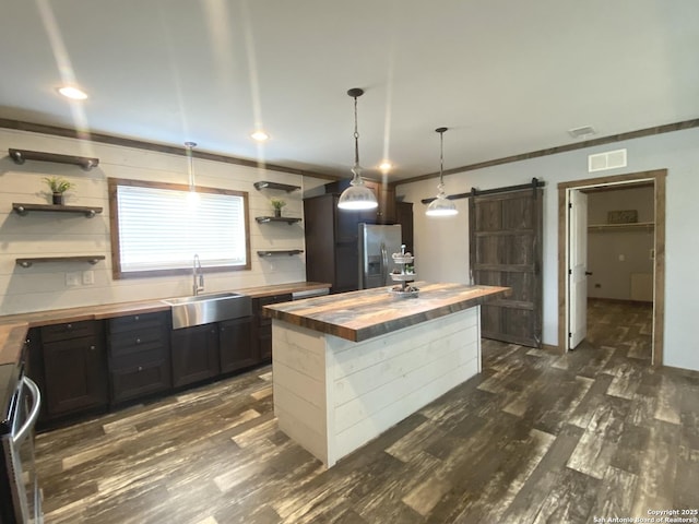 1727 Fm 1346, La Vernia, TX 78121 - kitchen with butcher block counters, a sink, stainless steel fridge with ice dispenser, open shelves, and a barn door