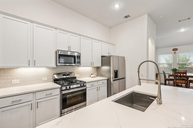10128 Bussang, Schertz, TX 78154 - kitchen with appliances with stainless steel finishes, a sink, backsplash, white cabinets, and light stone counters