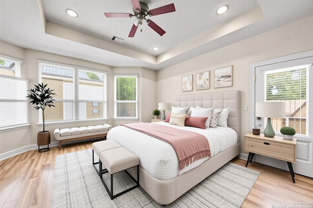 9927 Sandy Fld, San Antonio, TX 78245 - bedroom with a tray ceiling, light wood-style flooring, multiple windows, baseboards, and recessed lighting