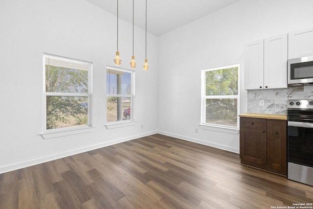 377 County Road 444, Hondo, TX 78861 - unfurnished dining area featuring dark wood-style floors, baseboards, and a towering ceiling