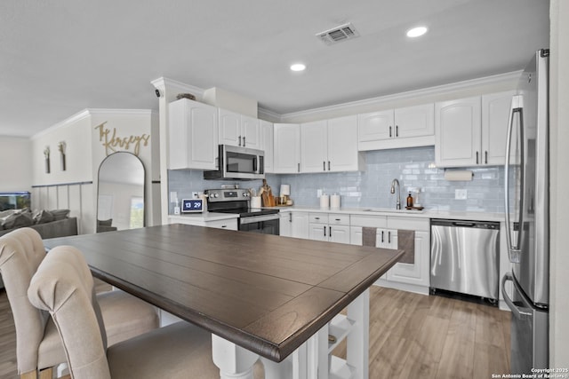 220 Glenvalley, Bandera, TX 78003 - kitchen with appliances with stainless steel finishes, a sink, ornamental molding, white cabinetry, and light wood finished floors