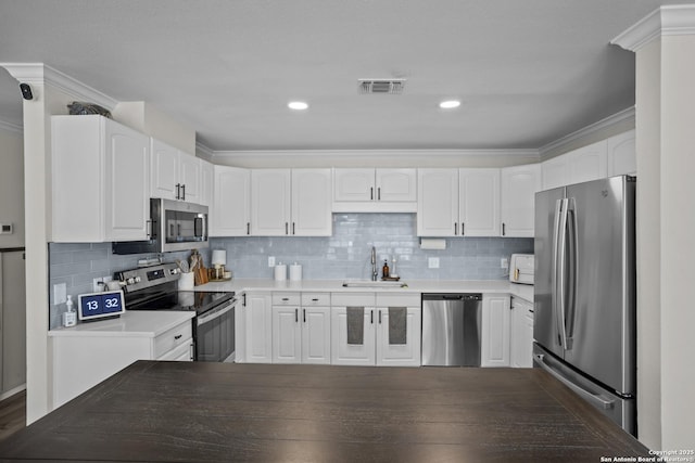 220 Glenvalley, Bandera, TX 78003 - kitchen featuring appliances with stainless steel finishes, a sink, white cabinets, tasteful backsplash, and crown molding