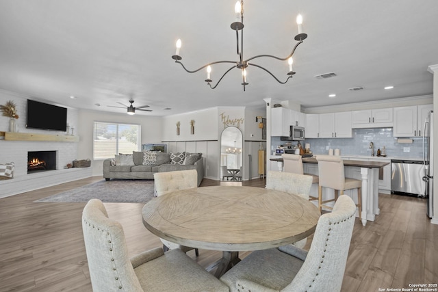 220 Glenvalley, Bandera, TX 78003 - dining space with ceiling fan, a chandelier, a fireplace, light wood finished floors, and recessed lighting