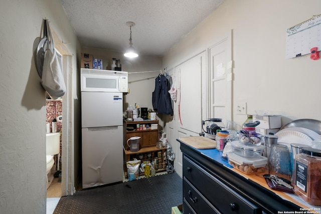 1230 Churing, San Antonio, TX 78245 - kitchen with freestanding refrigerator, white microwave, and a textured ceiling