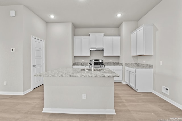 4267 Winston Way, New Braunfels, TX 78130 - kitchen with a sink, under cabinet range hood, stainless steel gas range oven, an island with sink, and white cabinets