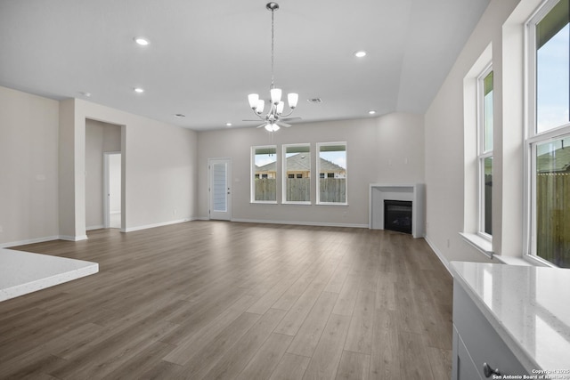13442 Cosette Xing, San Antonio, TX 78253 - unfurnished living room with a chandelier, a fireplace, wood finished floors, recessed lighting, and baseboards