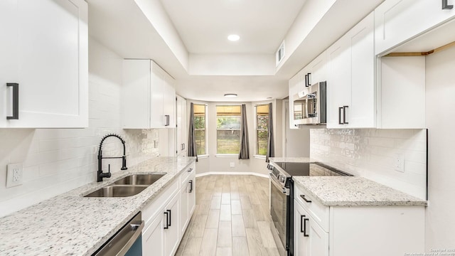 2130 Fort Sumter, San Antonio, TX 78245 - kitchen with appliances with stainless steel finishes, a sink, white cabinets, light stone counters, and recessed lighting
