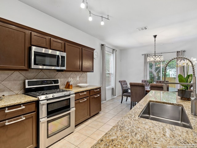 627 Midway, San Antonio, TX 78258 - kitchen with appliances with stainless steel finishes, light tile patterned flooring, a sink, and decorative backsplash