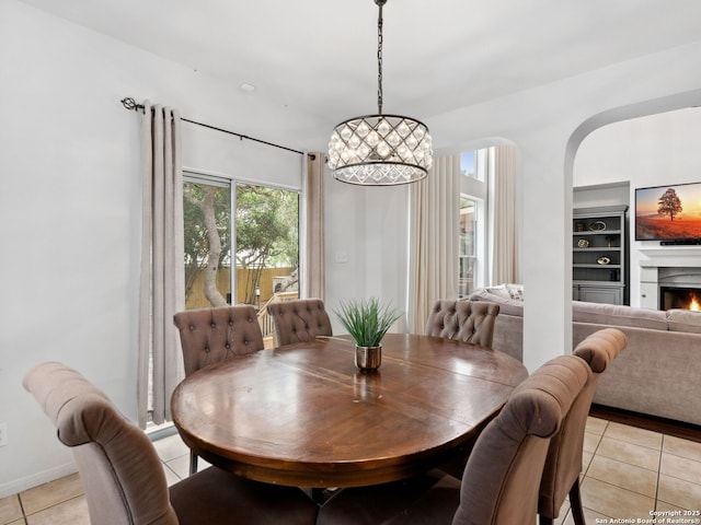 627 Midway, San Antonio, TX 78258 - dining area with light tile patterned floors, a warm lit fireplace, arched walkways, and baseboards