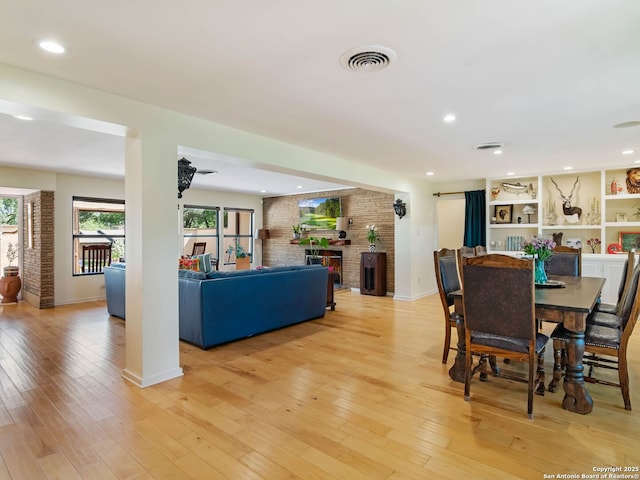 134 Camellia Way, San Antonio, TX 78209 - dining space with a fireplace, light wood-style floors, baseboards, brick wall, and recessed lighting