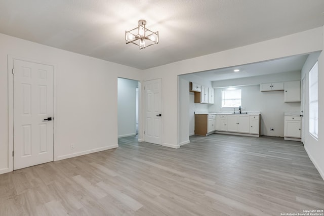 7126 Westbriar, San Antonio, TX 78227 - unfurnished living room with a sink, light wood-style floors, baseboards, and a chandelier