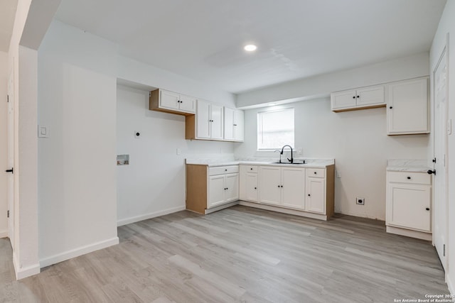 7126 Westbriar, San Antonio, TX 78227 - kitchen with light wood-style flooring, white cabinets, light countertops, a sink, and baseboards