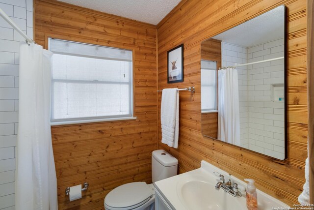 577 Dusty Saddle, Canyon Lake, TX 78133 - full bath featuring wooden walls, toilet, vanity, a shower with shower curtain, and a textured ceiling