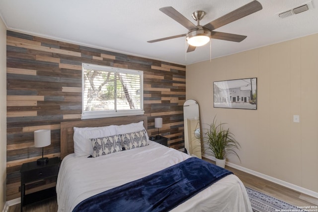 577 Dusty Saddle, Canyon Lake, TX 78133 - bedroom with wood walls, baseboards, wood finished floors, an accent wall, and ceiling fan