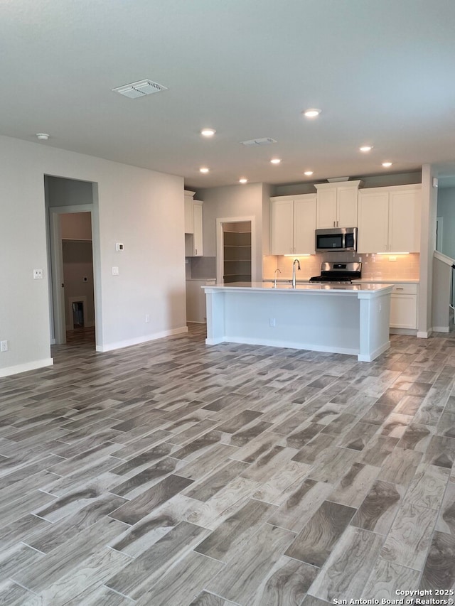 759 Fort Leonard, San Antonio, TX 78245 - kitchen with appliances with stainless steel finishes, white cabinets, light wood-style floors, a kitchen island with sink, and recessed lighting
