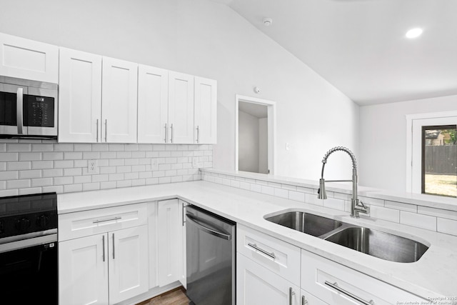11403 Big Elk, San Antonio, TX 78245 - kitchen with appliances with stainless steel finishes, a sink, vaulted ceiling, white cabinets, and decorative backsplash