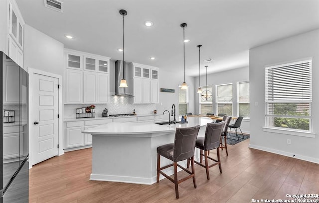 2818 Tortuga Verde, San Antonio, TX 78245 - kitchen with wall chimney range hood, black refrigerator, gas cooktop, a sink, and light wood-type flooring