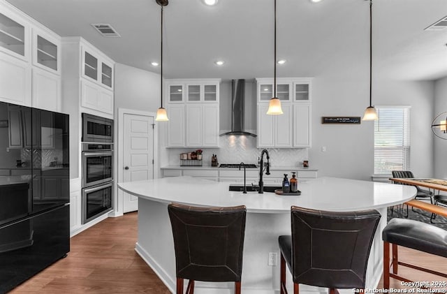 2818 Tortuga Verde, San Antonio, TX 78245 - kitchen with wall chimney range hood, stainless steel appliances, tasteful backsplash, dark wood-type flooring, and light countertops