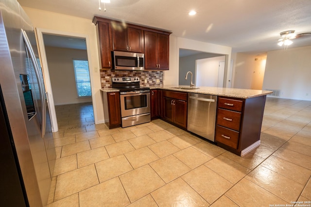 902 Newhall, Beeville, TX 78102 - kitchen featuring stainless steel appliances, a sink, a peninsula, decorative backsplash, and light stone countertops