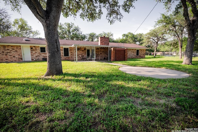 902 Newhall, Beeville, TX 78102 - view of front of home with a chimney, a front yard, brick siding, and a patio area