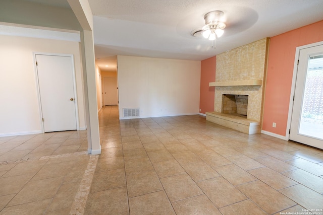 902 Newhall, Beeville, TX 78102 - unfurnished living room with ceiling fan, light tile patterned floors, a large fireplace, and plenty of natural light