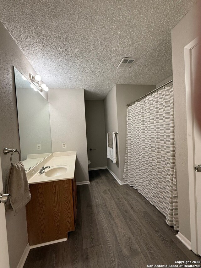 130 Nedrub Dr, San Antonio, TX 78223 - full bathroom with wood finished floors, vanity, a textured ceiling, toilet, and baseboards
