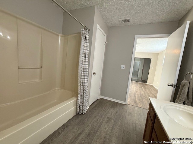 130 Nedrub Dr, San Antonio, TX 78223 - bathroom with wood finished floors, shower / bath combination with curtain, vanity, and a textured ceiling