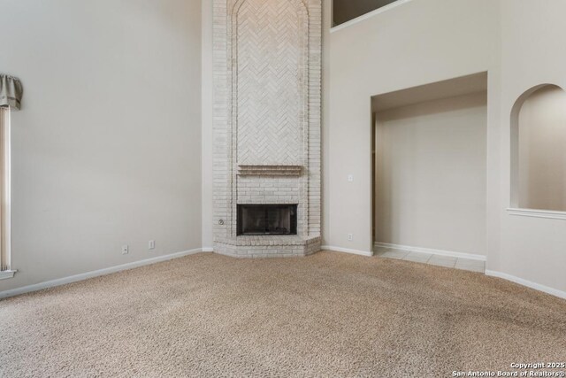 2614 Inwood Vw, San Antonio, TX 78248 - unfurnished living room with carpet flooring, a brick fireplace, a towering ceiling, and baseboards