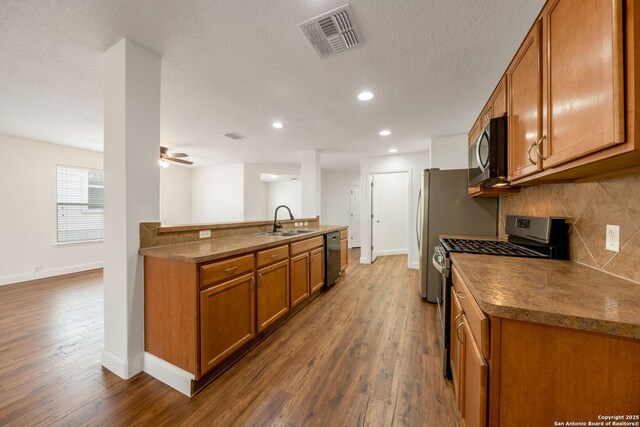 10911 Shoo Fly Trl, San Antonio, TX 78245 - kitchen featuring stainless steel appliances, brown cabinets, dark wood-type flooring, decorative backsplash, and recessed lighting