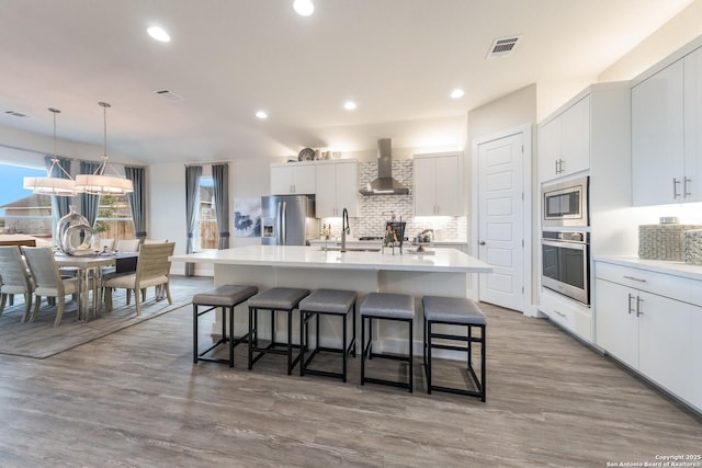 379 Borchers Blvd, New Braunfels, TX 78132 - kitchen featuring stainless steel appliances, wall chimney exhaust hood, a sink, a breakfast bar area, and tasteful backsplash