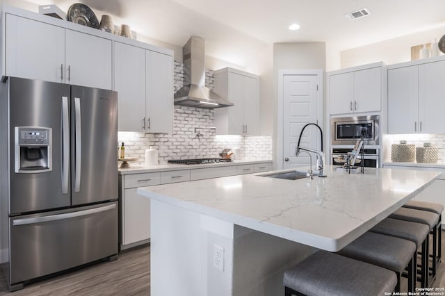 379 Borchers Blvd, New Braunfels, TX 78132 - kitchen with stainless steel appliances, wall chimney exhaust hood, a sink, a kitchen bar, and backsplash