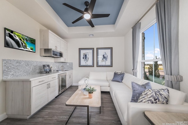 379 Borchers Blvd, New Braunfels, TX 78132 - living area featuring wine cooler, dark wood-style floors, baseboards, a ceiling fan, and a raised ceiling