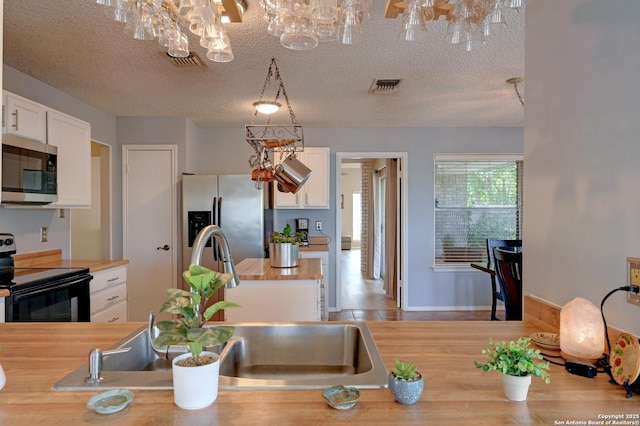 3734 Colter, San Antonio, TX 78247 - kitchen with stainless steel appliances, butcher block counters, white cabinetry, a sink, and a chandelier
