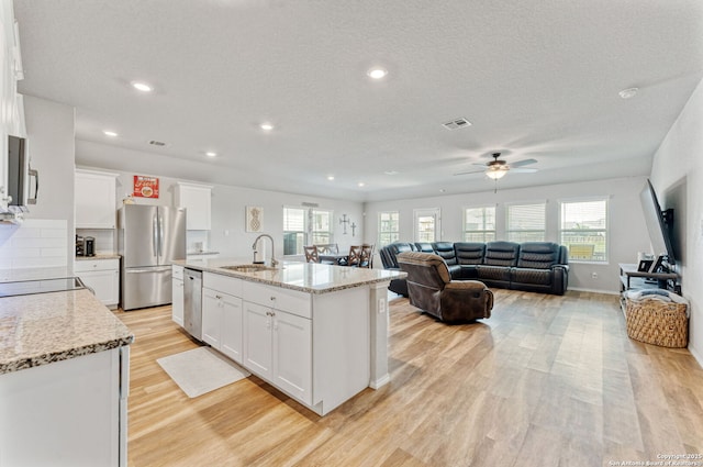 2946 Daisy Mdw, New Braunfels, TX 78130 - kitchen with appliances with stainless steel finishes, a sink, light wood finished floors, ceiling fan, and white cabinets