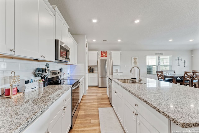 2946 Daisy Mdw, New Braunfels, TX 78130 - kitchen with appliances with stainless steel finishes, a sink, light wood finished floors, white cabinets, and recessed lighting