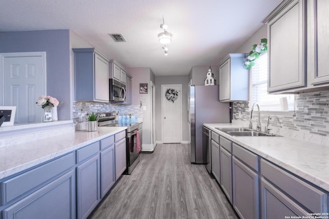 5634 Forest Cyn, San Antonio, TX 78252 - kitchen featuring appliances with stainless steel finishes, a sink, tasteful backsplash, light wood-style flooring, and baseboards