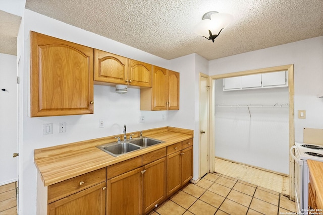 11415 Rousseau St, San Antonio, TX 78251 - kitchen with a sink, white electric stove, a textured ceiling, light tile patterned floors, and brown cabinetry