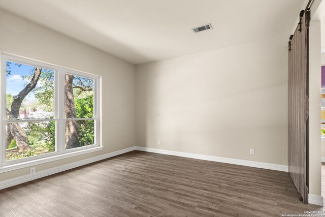 122 Kettle Cv, Universal City, TX 78148 - empty room featuring a barn door, dark wood finished floors, and baseboards
