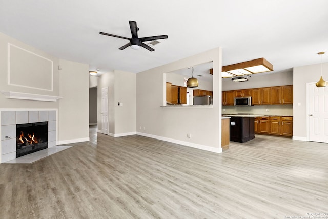 122 Kettle Cv, Universal City, TX 78148 - unfurnished living room with light wood-type flooring, ceiling fan, a tile fireplace, and baseboards