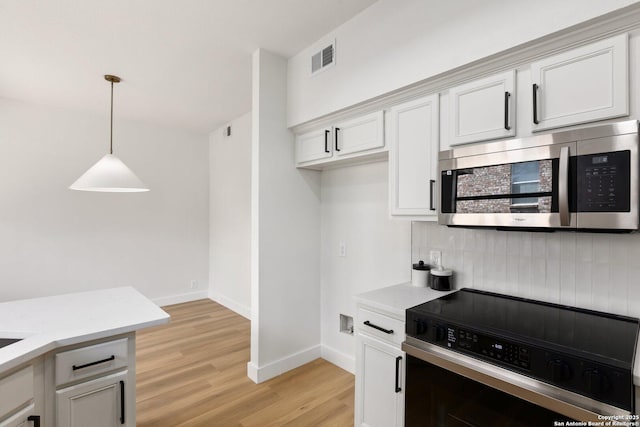 959 Lightstone Dr, San Antonio, TX 78258 - kitchen with stainless steel microwave, range, light wood-style floors, backsplash, and pendant lighting