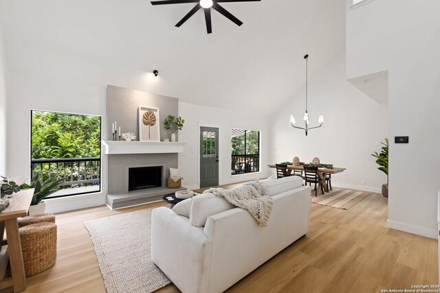 959 Lightstone Dr, San Antonio, TX 78258 - living room with high vaulted ceiling, a fireplace with raised hearth, light wood-style flooring, a chandelier, and a ceiling fan