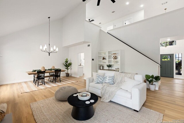 959 Lightstone Dr, San Antonio, TX 78258 - living room with a high ceiling, light wood-style flooring, a chandelier, a ceiling fan, and baseboards