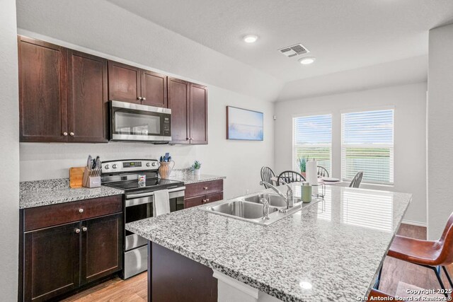 712 Monarch, Seguin, TX 78155 - kitchen with appliances with stainless steel finishes, a sink, light wood-style floors, a kitchen breakfast bar, and an island with sink