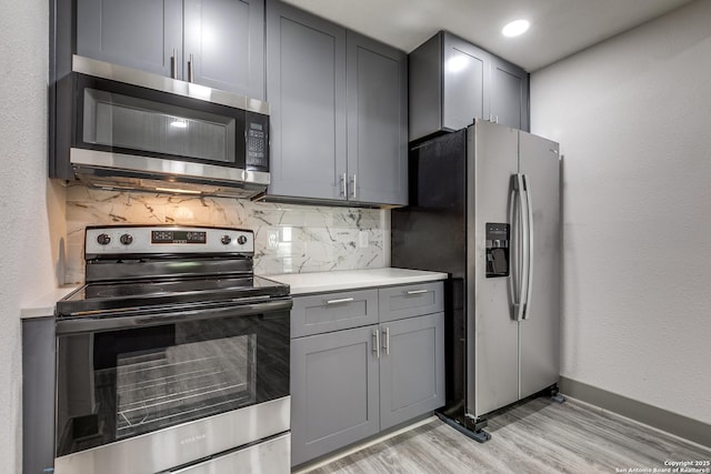 2822 Spokane, San Antonio, TX 78222 - kitchen featuring stainless steel appliances, gray cabinetry, backsplash, light countertops, and light wood-style flooring