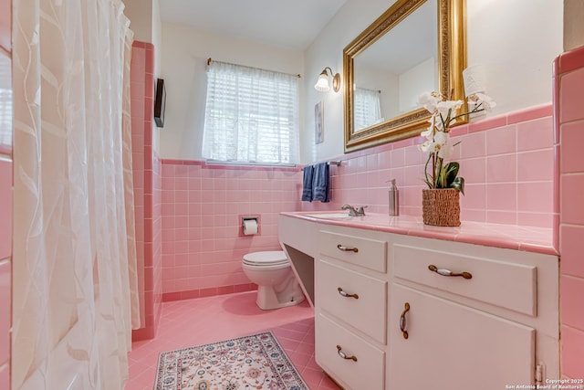 438 Cosgrove, San Antonio, TX 78210 - bathroom with tile patterned floors, toilet, vanity, tile walls, and a wainscoted wall