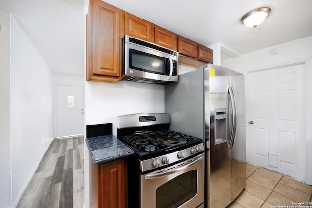 429 Aviation, Universal City, TX 78148 - kitchen with stainless steel appliances, brown cabinets, dark stone countertops, light wood-type flooring, and baseboards