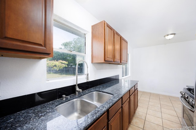 429 Aviation, Universal City, TX 78148 - kitchen featuring stainless steel range with gas cooktop, a sink, light tile patterned flooring, dark stone counters, and brown cabinetry