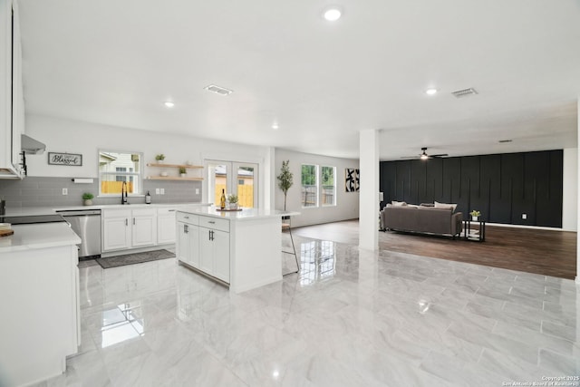 242 Butternut, San Antonio, TX 78245 - kitchen with stainless steel dishwasher, white cabinetry, light countertops, ceiling fan, and open floor plan